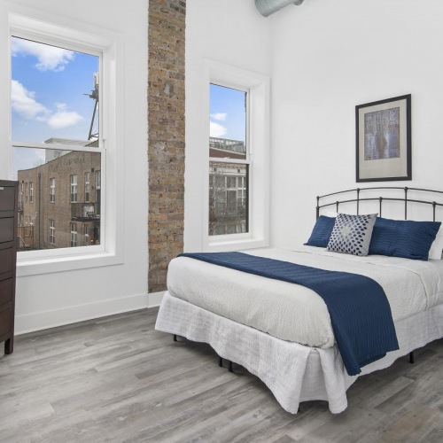 spacious bedroom with a bed and windows