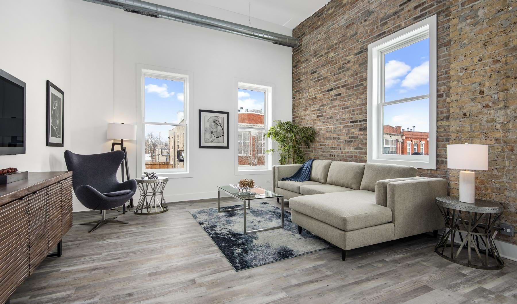 a living room with a stone wall and natural lighting from surrounding windows